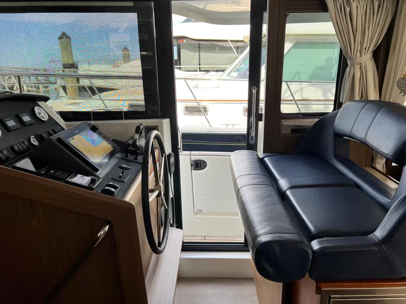 Slide: The Image of 2019 Beneteau Swift Trawler 44 helm with leather seating and navigation controls. - 6