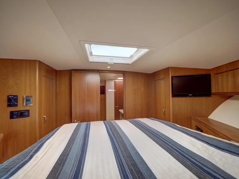 Slide: The Image of Cabo HTX 2013 yacht cabin with striped bedding, skylight, and wall-mounted TV. - 15