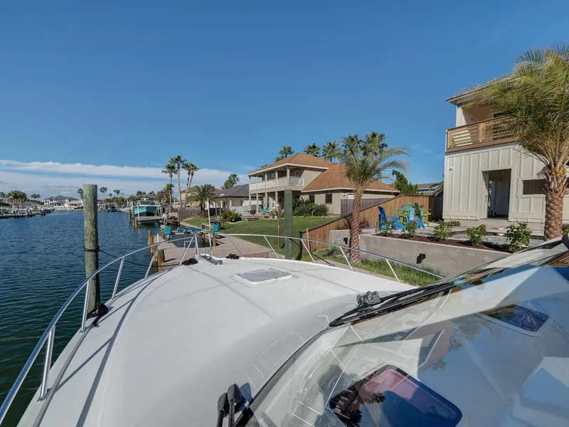 Slide: The Image of Cabo HTX 2013 yacht docked near waterfront homes with palm trees and clear skies. - 21