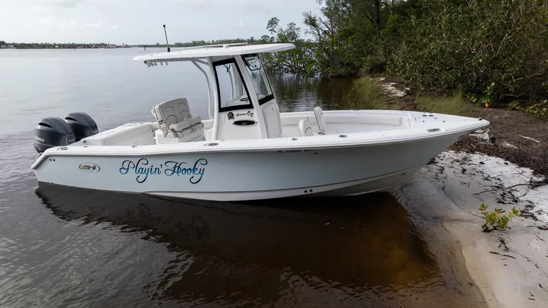 Slide: The Image of 2021 Sea Hunt Gamefish 25 boat on sandy shore, twin engines, calm water. - 0