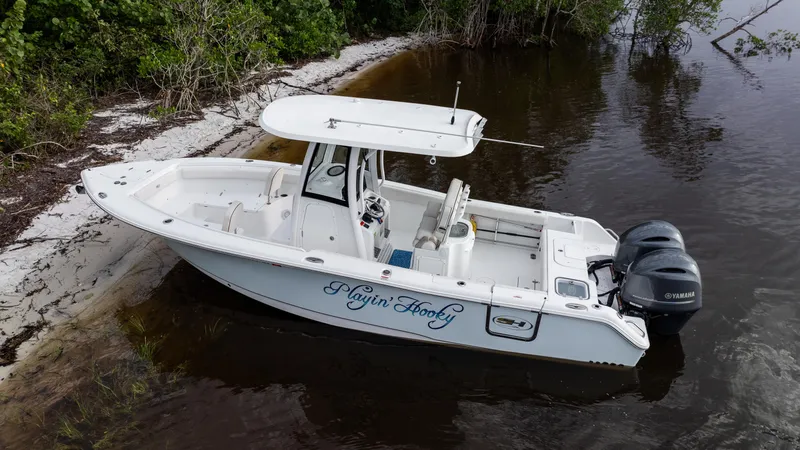 Slide: The Image of 2021 Sea Hunt Gamefish 25 boat with dual engines docked by a sandy shore. - 37