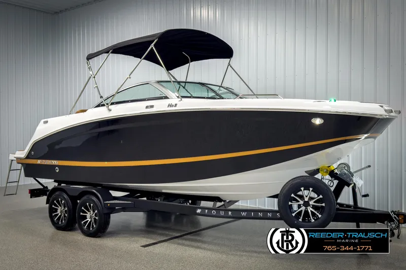 Slide: The Image of 2025 Four Winns HD3 boat on trailer in showroom, black and white design, with canopy. - 3