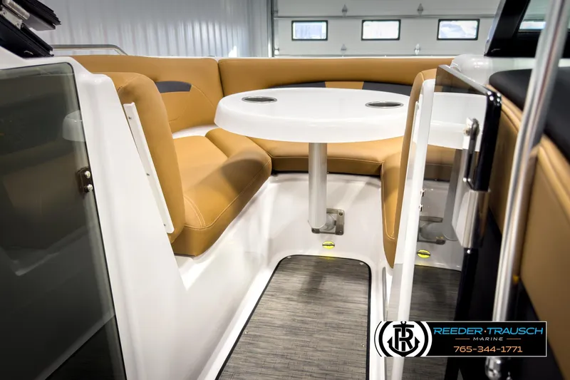 Slide: The Image of 2025 Four Winns HD3 boat interior with tan seating and white table in a showroom. - 47