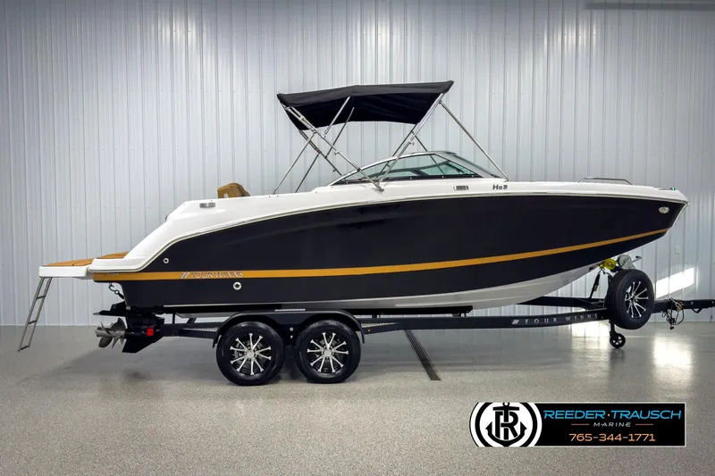 Slide: The Image of 2025 Four Winns HD3 boat on trailer in showroom, black and white design. - 5