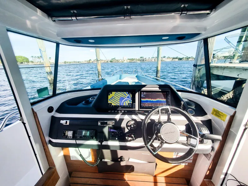 Slide: The Image of 2021 Axopar 28 CABIN boat interior with steering wheel and navigation screens. - 11