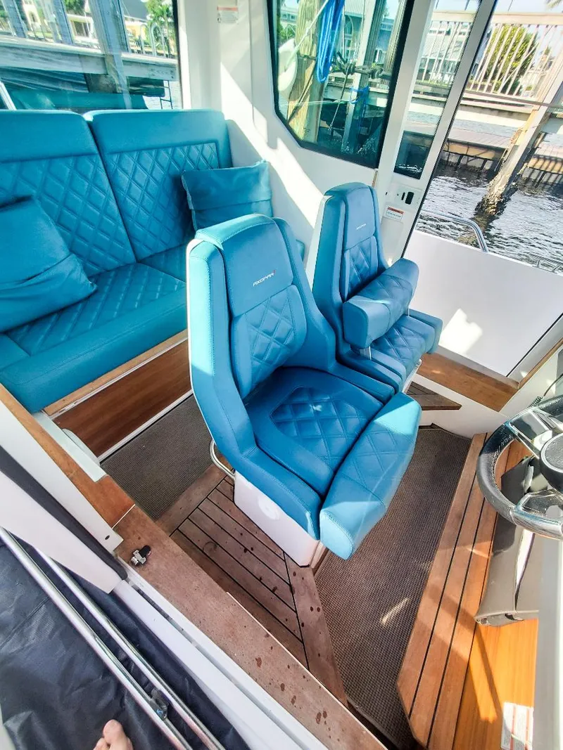 Slide: The Image of 2021 Axopar 28 CABIN interior with blue seating and wooden flooring. - 13