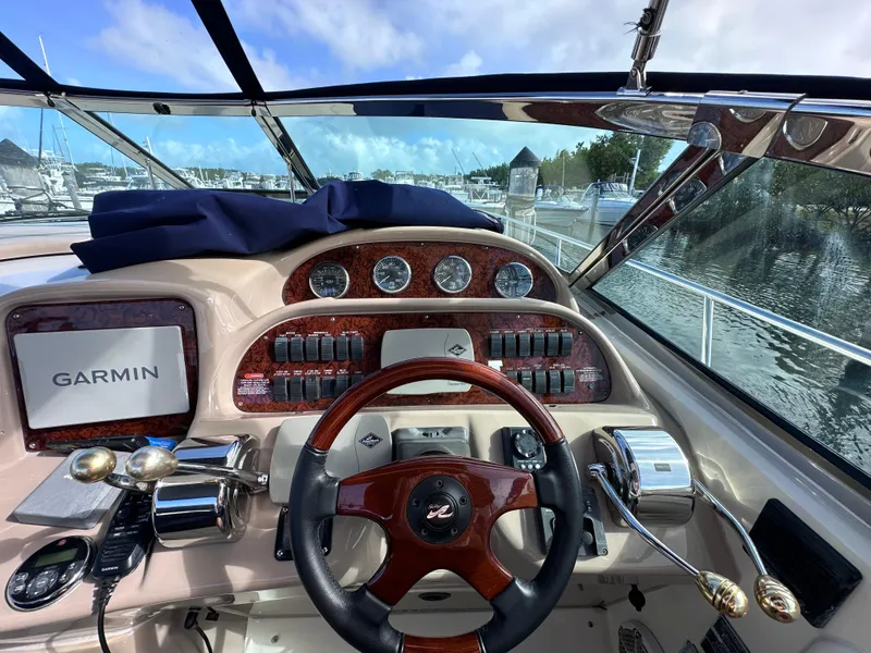 Slide: The Image of 2004 Sea Ray 360 Sundancer helm with Garmin navigation, wood accents, and marina view. - 12