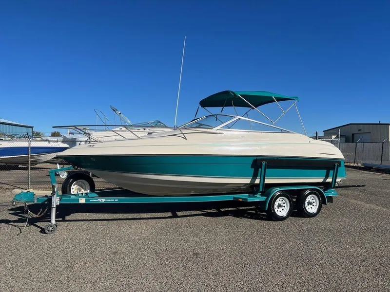 Slide: The Image of 1995 Regal Valanti 222 boat on trailer, teal and white, parked outdoors. - 1