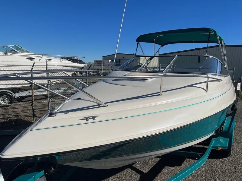 Slide: The Image of 1995 Regal Valanti 222 boat with teal accents and canopy, parked outdoors. - 3