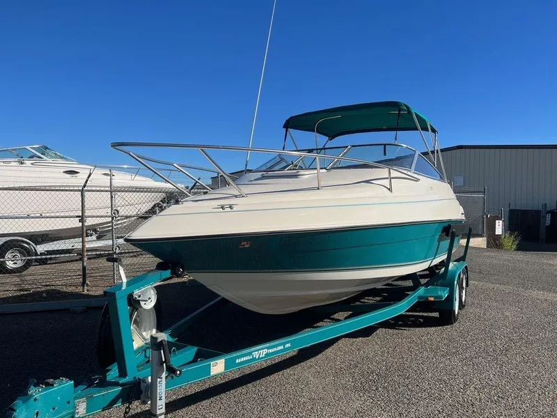 Slide: The Image of 1995 Regal Valanti 222 boat on trailer, parked outdoors under clear blue sky. - 4