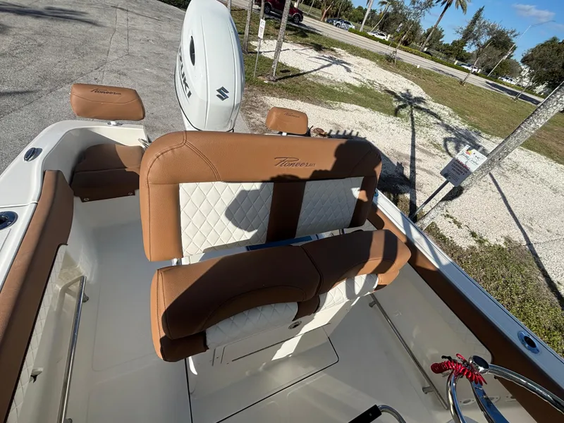 Slide: The Image of 2025 Pioneer 202 Sportfish boat interior with brown and white seating, parked outdoors. - 10