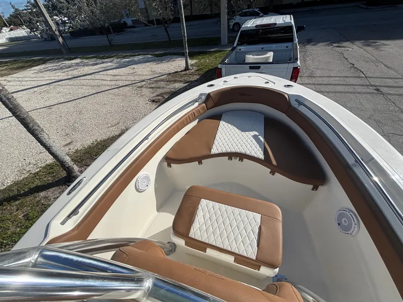 Slide: The Image of 2025 Pioneer 202 Sportfish boat interior with tan and white seating, parked near a truck. - 13