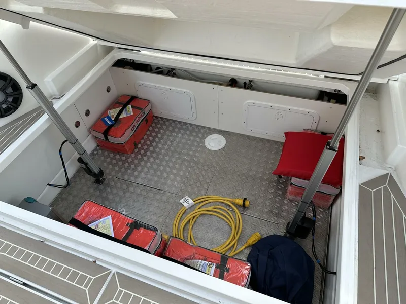 Slide: The Image of Open storage compartment in 2022 Nimbus T-11 boat with safety equipment and cables. - 11