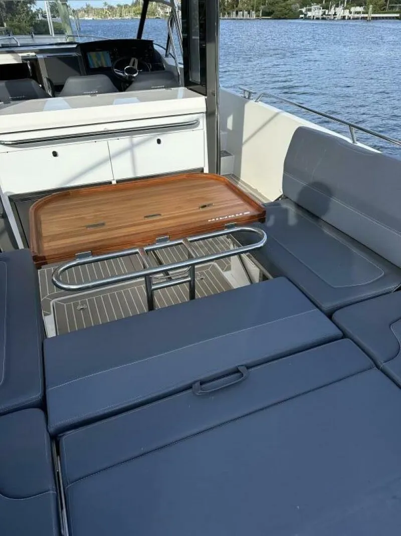 Slide: The Image of Luxurious 2022 Nimbus T-11 boat interior with sleek seating and wooden table by the water. - 19