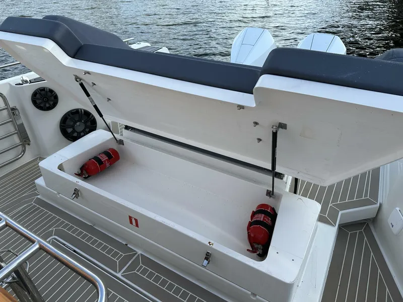 Slide: The Image of Open storage compartment on 2022 Nimbus T-11 boat with fire extinguishers. - 21