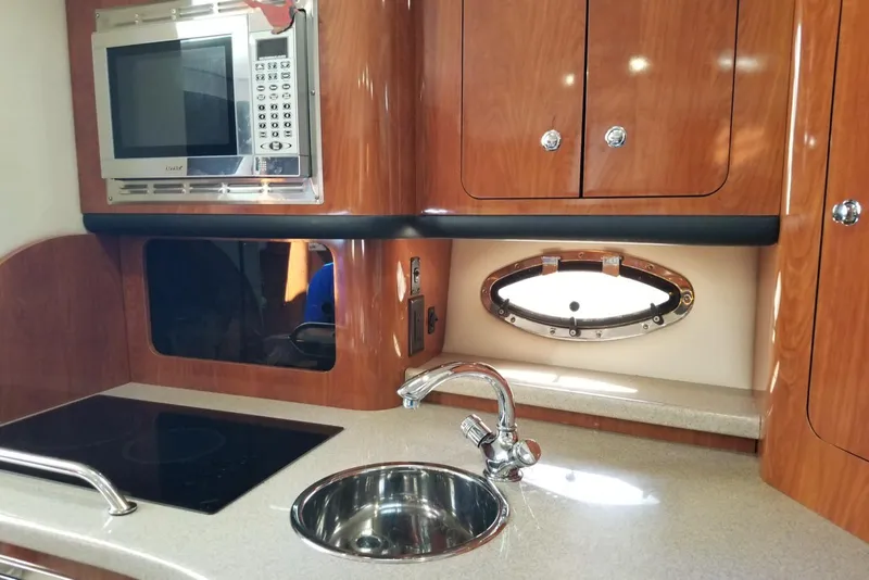 Slide: The Image of 2007 Crownline 340 CR yacht kitchen with microwave, sink, and stove. - 18
