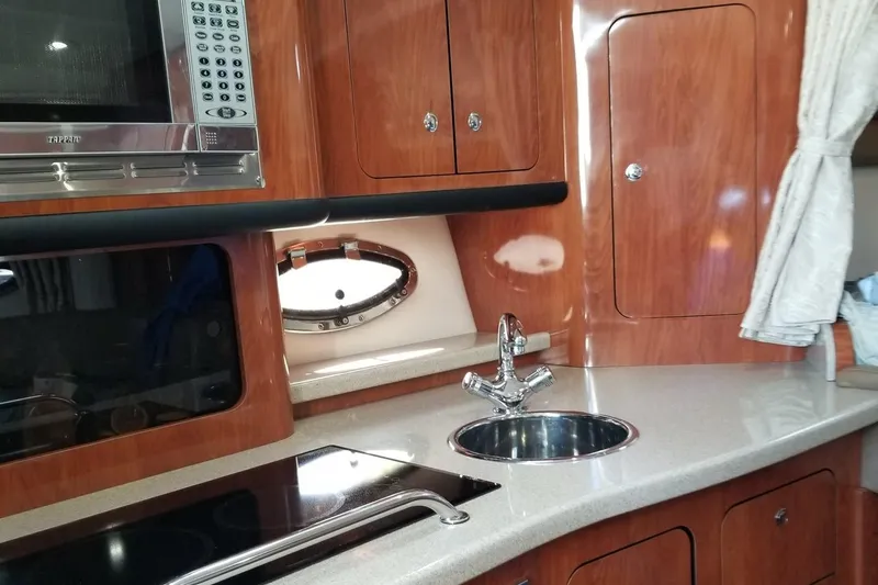 Slide: The Image of 2007 Crownline 340 CR yacht kitchen with wood cabinets, sink, and microwave. - 19