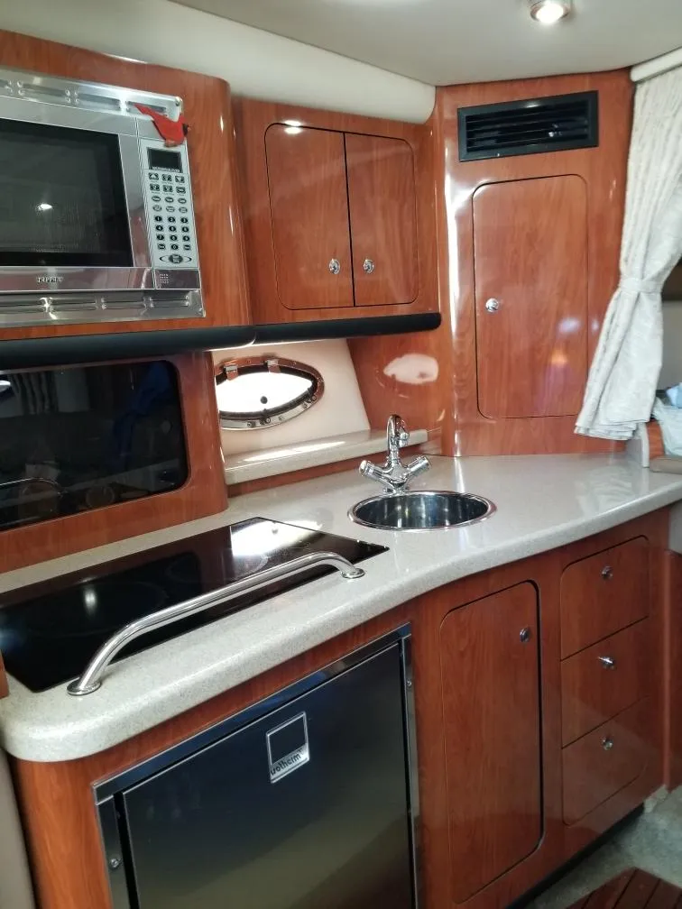 Slide: The Image of 2007 Crownline 340 CR yacht kitchen with microwave, sink, and wooden cabinetry. - 21
