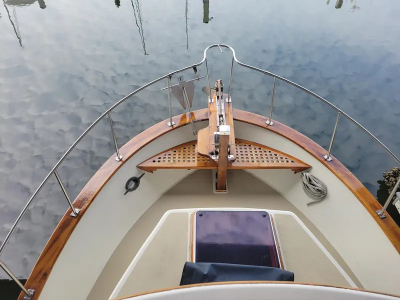 Slide: The Image of 1983 Marine Trader 34 Trawler bow view with wooden deck and calm water reflection. - 11