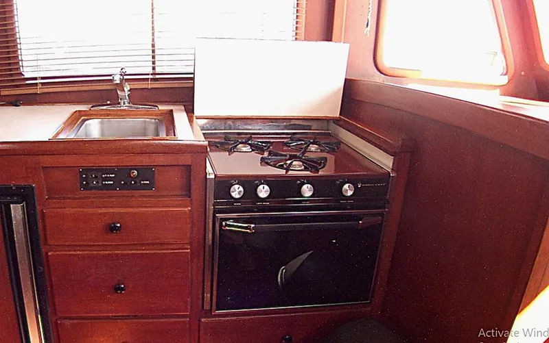 Slide: The Image of 1983 Marine Trader 34 Trawler kitchen with stove, sink, and wooden cabinetry. - 18