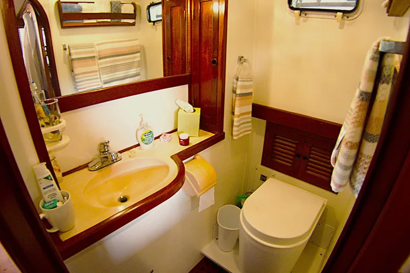 Slide: The Image of 1983 Marine Trader 34 Trawler bathroom with sink, toilet, and wooden accents. - 26