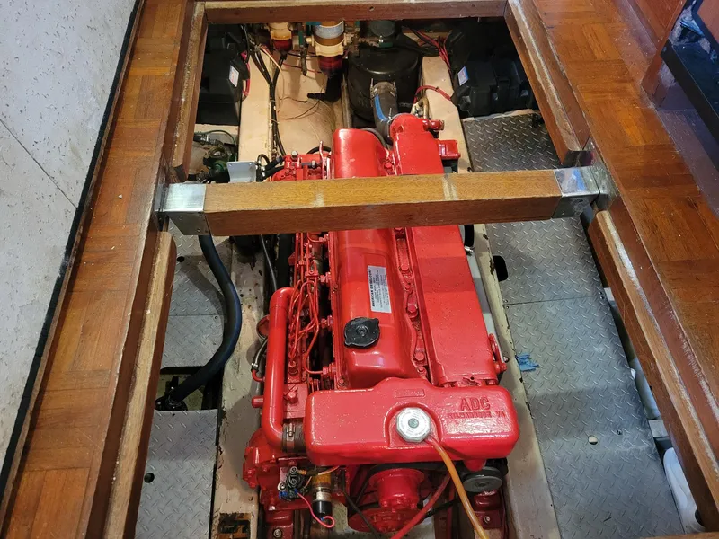 Slide: The Image of 1983 Marine Trader 34 Trawler engine, red, under wooden floor panels. - 29