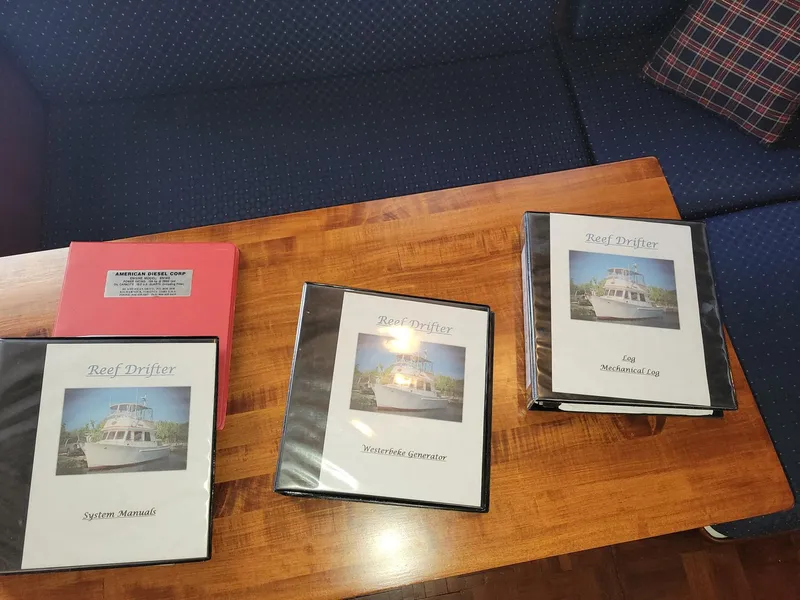Slide: The Image of Binders on a wooden table with manuals for 1983 Marine Trader 34 Trawler. - 36