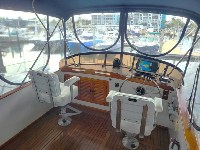 Slide: The Image of 1983 Marine Trader 34 Trawler helm with navigation equipment and marina view. - 8
