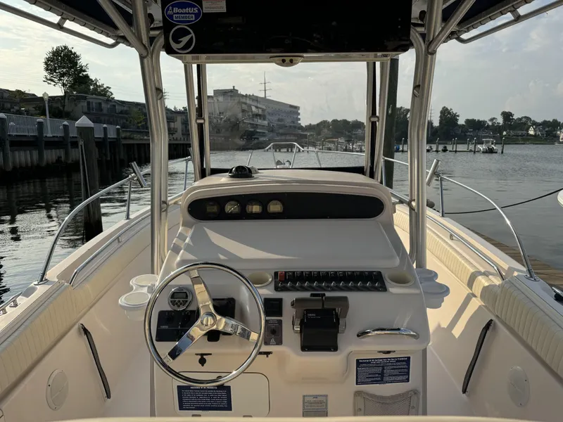 Slide: The Image of 2004 Grady-White Release 283 boat cockpit with steering wheel and control panel, docked by the water. - 7