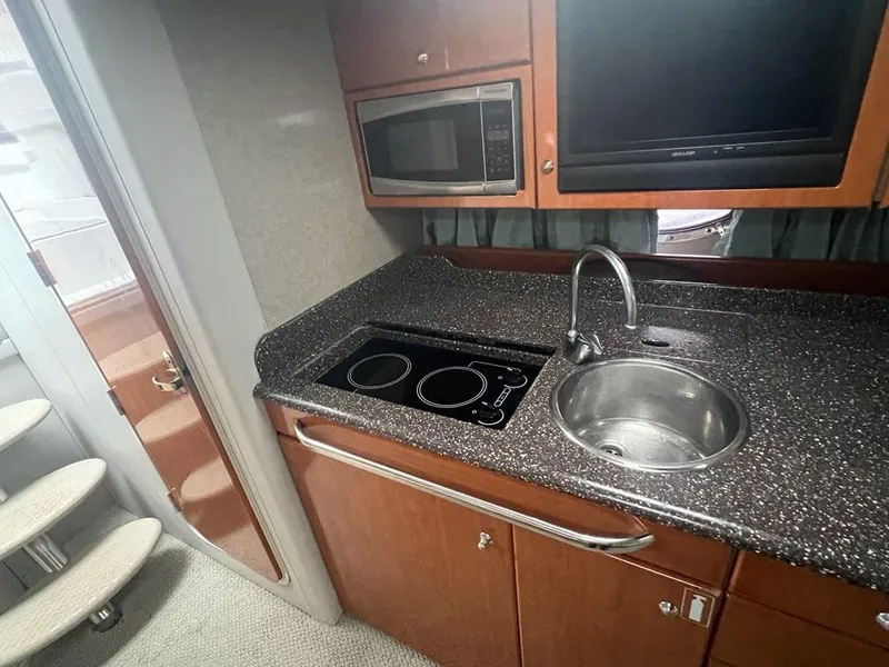 Slide: The Image of 2004 Formula 34 PC yacht kitchen with sink, stovetop, microwave, and TV. - 17