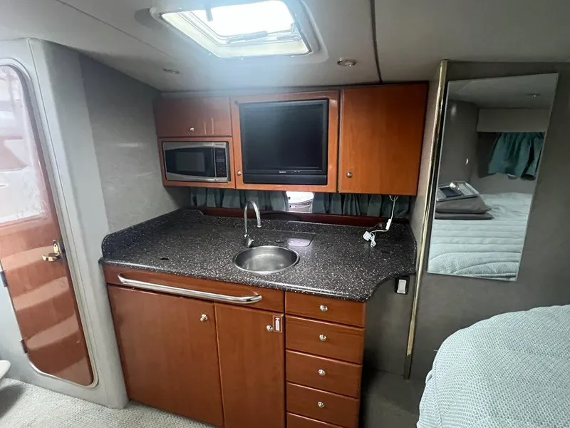 Slide: The Image of 2004 Formula 34 PC yacht interior with kitchenette, featuring wood cabinets and modern appliances. - 18