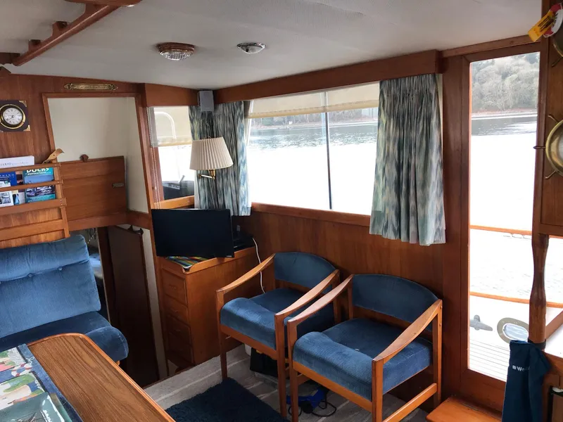 Slide: The Image of Interior of a 1969 Grand Banks 42 Classic yacht with wooden furnishings and blue seating. - 13