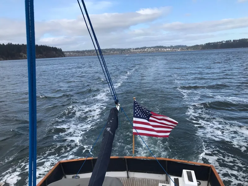 Slide: The Image of Grand Banks 42 Classic yacht cruising with American flag, 1969 model, scenic water view. - 36