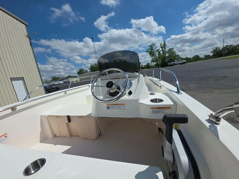 Slide: The Image of 2025 Boston Whaler 160 Super Sport boat interior with steering wheel, parked outdoors under blue sky. - 6