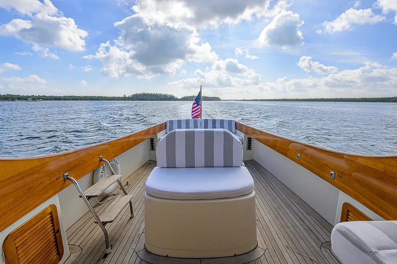 Slide: The Image of 2000 Hinckley Picnic Boat Classic on serene water, featuring elegant wooden deck and striped seating. - 10