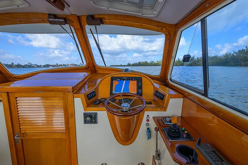 Slide: The Image of 2000 Hinckley Picnic Boat Classic helm with wooden dashboard and navigation system, overlooking serene waters. - 12