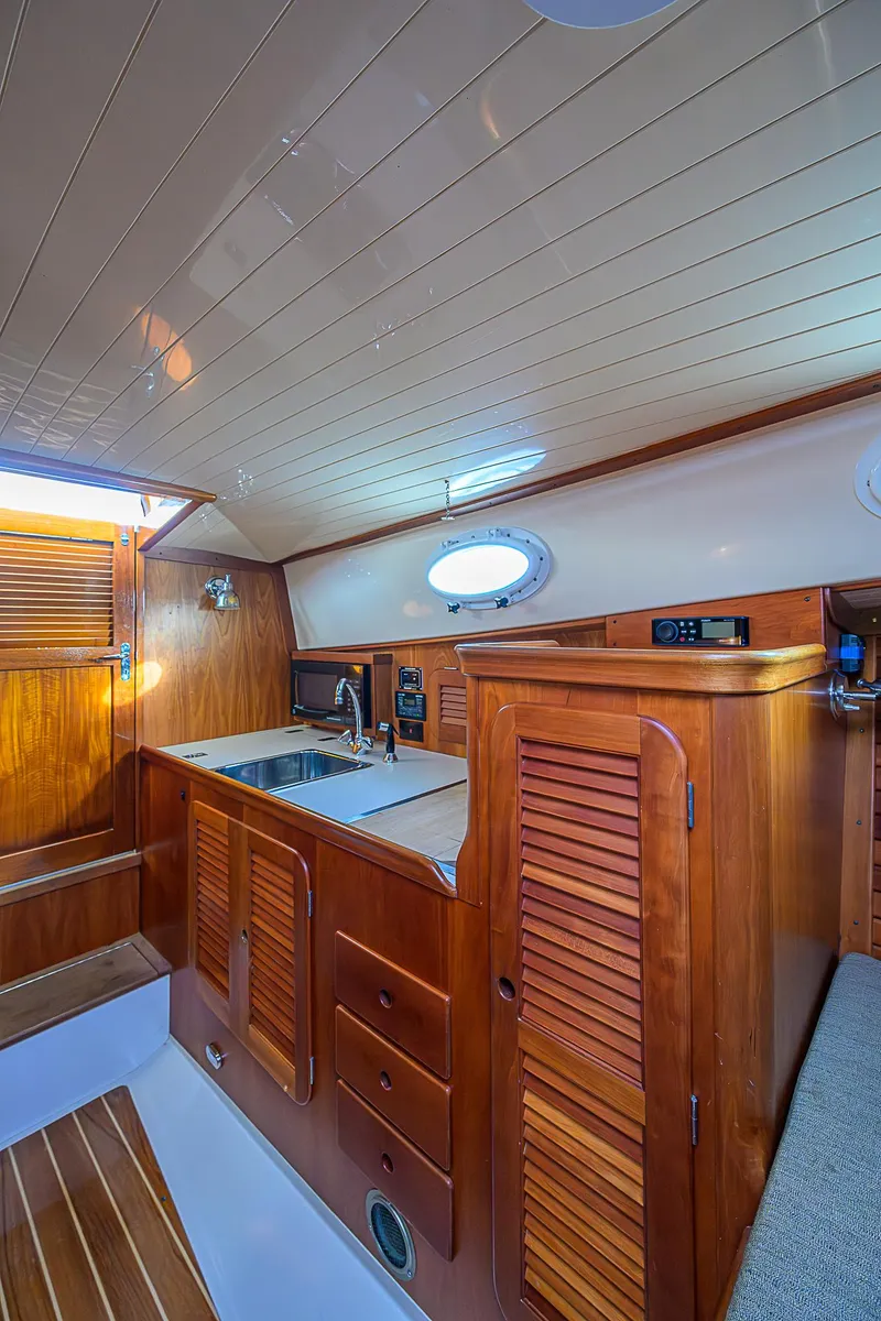 Slide: The Image of Interior of 2000 Hinckley Picnic Boat Classic with wooden cabinetry and compact kitchen area. - 14