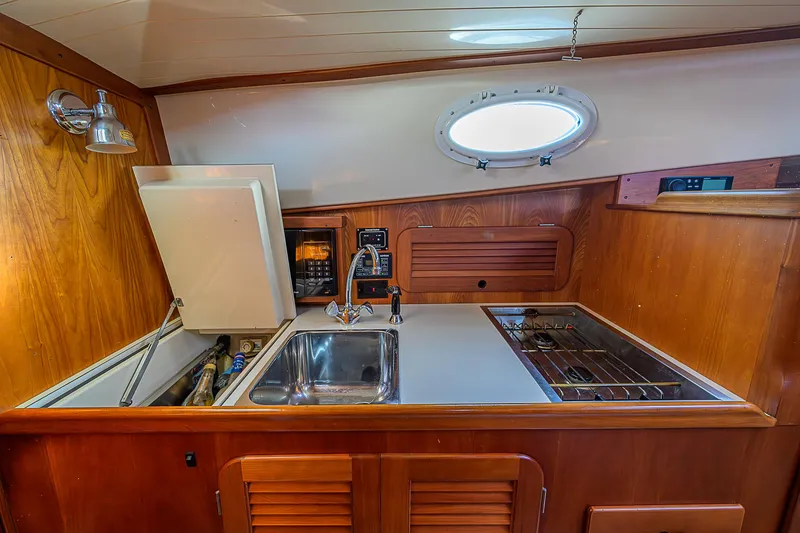 Slide: The Image of 2000 Hinckley Picnic Boat Classic interior galley with sink, stove, and wooden cabinetry. - 16
