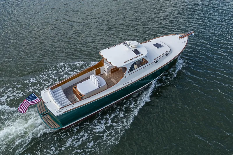 Slide: The Image of Hinckley Picnic Boat Classic 2000 cruising on water, featuring elegant design and American flag. - 24