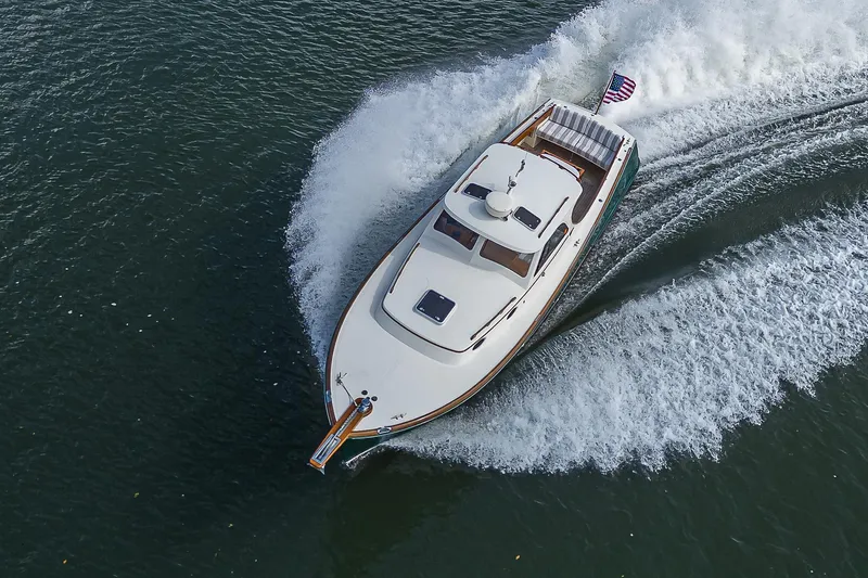 Slide: The Image of Hinckley Picnic Boat Classic 2000 cruising on water, aerial view, American flag visible. - 25