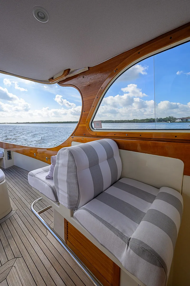 Slide: The Image of Hinckley Picnic Boat Classic 2000 interior with striped seating, wooden accents, and scenic water view. - 9