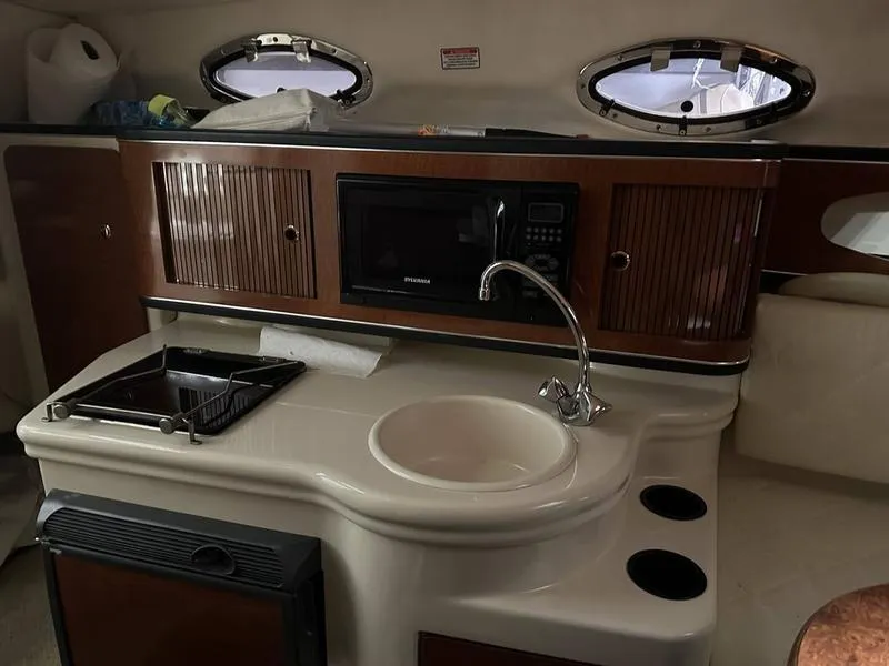 Slide: The Image of Interior of 2004 Sea Ray 260 Sundancer with cushioned seating and porthole window. - 15