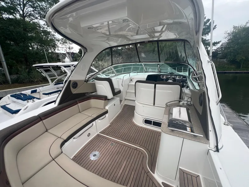 Slide: The Image of 2016 Sea Ray 370 Sundancer boat interior with seating and helm, docked by the water. - 13
