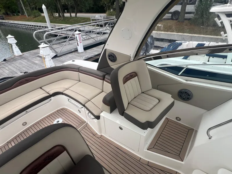 Slide: The Image of 2016 Sea Ray 370 Sundancer boat interior with beige seating and wood accents at a dock. - 15