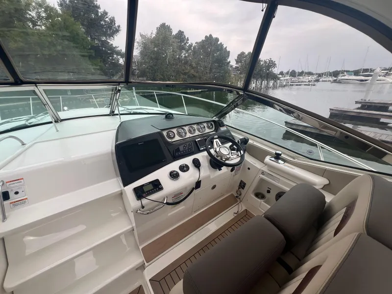 Slide: The Image of 2016 Sea Ray 370 Sundancer helm with modern controls, docked by a serene marina. - 16