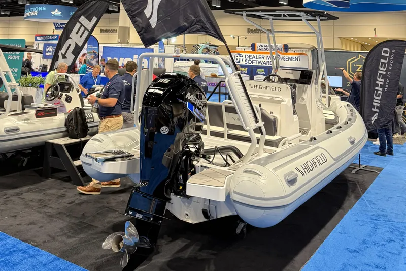 The Image of 2025 Highfield Sport 560 boat displayed at a trade show with attendees. - 0