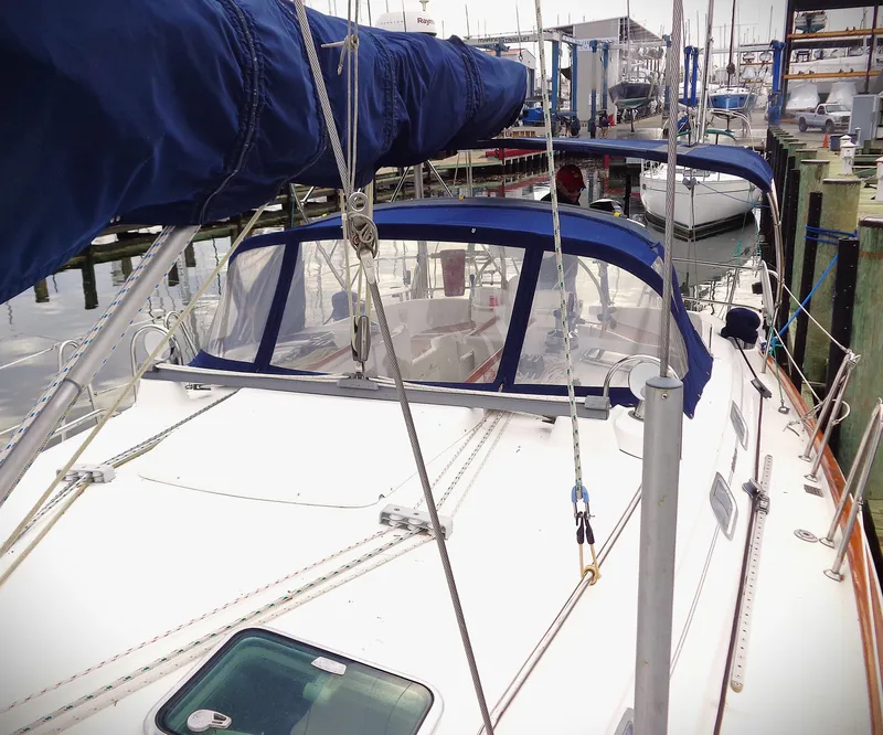 Slide: The Image of 2002 Beneteau 411 sailboat docked, featuring blue canvas covers and sleek design. - 18