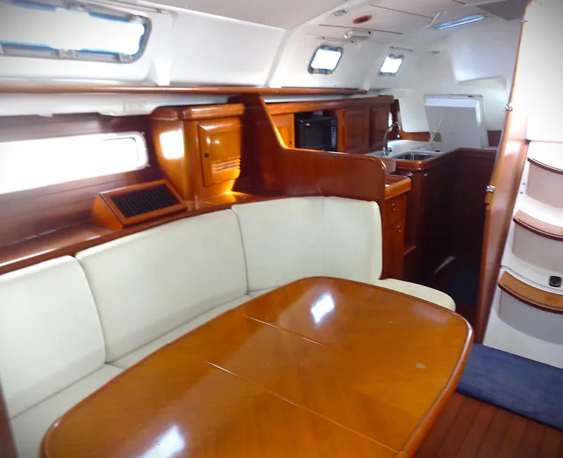 Slide: The Image of Interior of 2002 Beneteau 411 yacht with wooden dining table and white seating. - 4