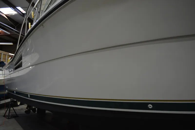 Slide: The Image of 1999 Pursuit 3400 Express boat in a dimly lit indoor storage facility. - 20