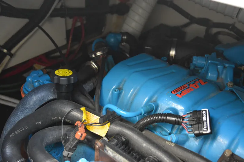 Slide: The Image of Engine compartment of a 1999 Pursuit 3400 Express boat, featuring blue components and wiring. - 48
